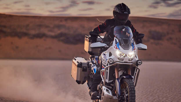 Motoros a Honda CRF1100 Africa Twin Adventure Sports nyergében, sivatagi környezetben.